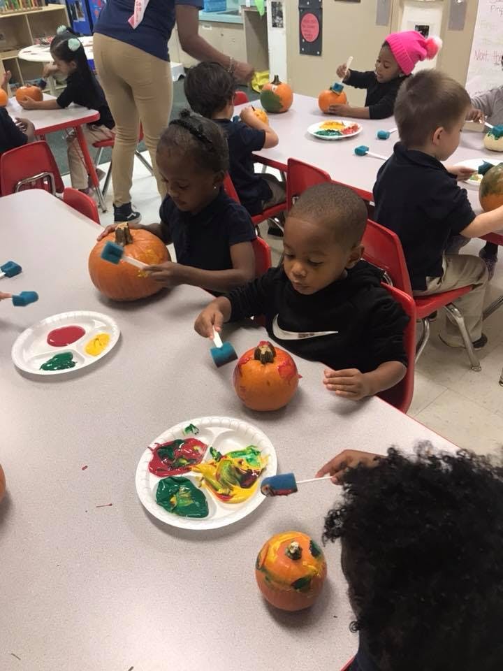 Children painting pumpkins at a table