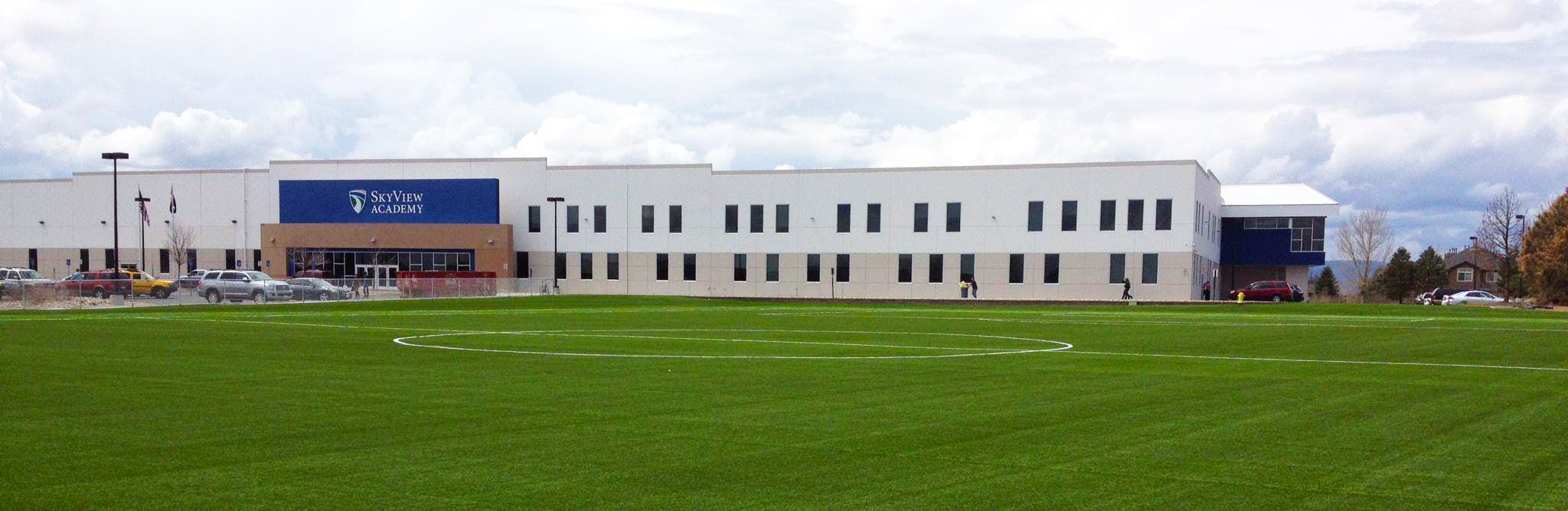 Building with a large green field in front