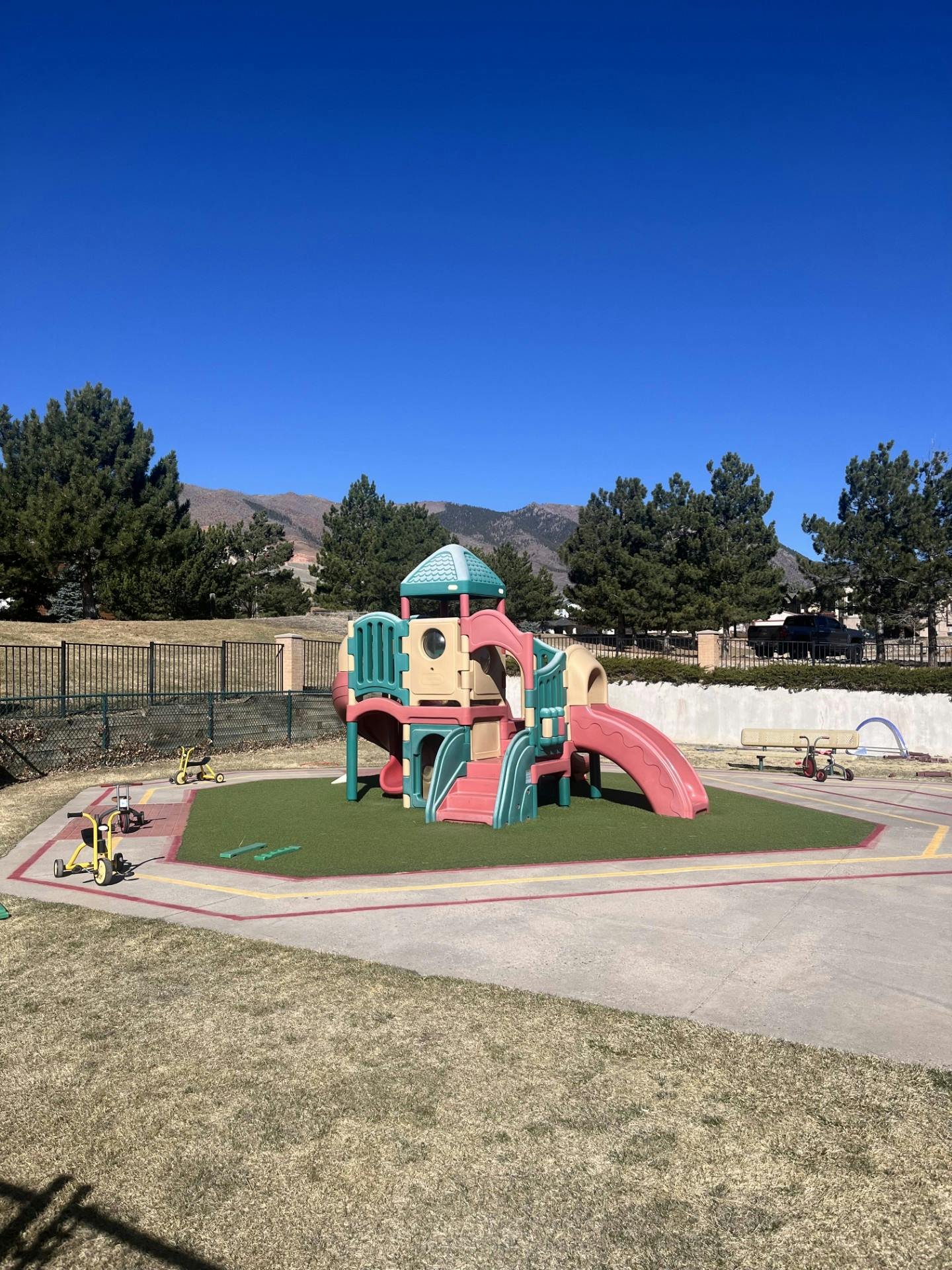 Playground with a colorful play structure, slides, and tricycles on a sunny day