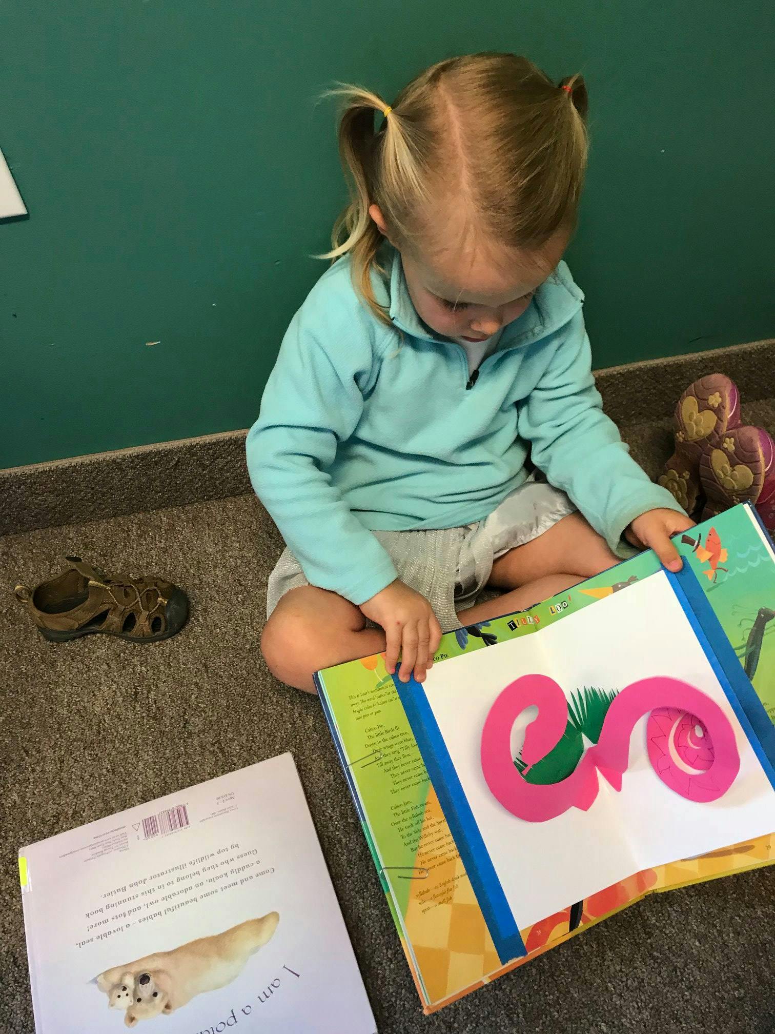 Child sitting on floor looking at a pop-up book