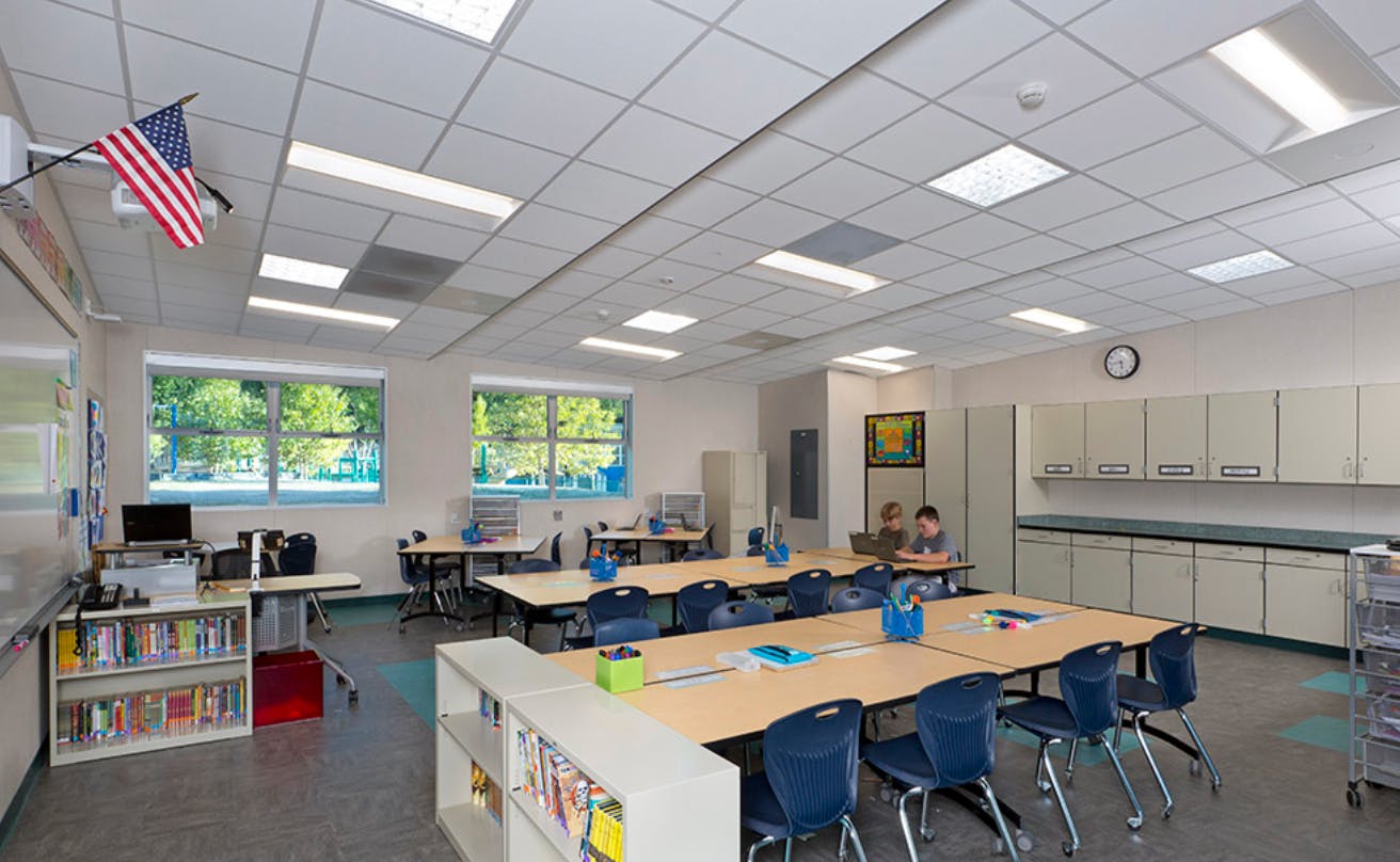 Empty classroom with tables, chairs, and an American flag