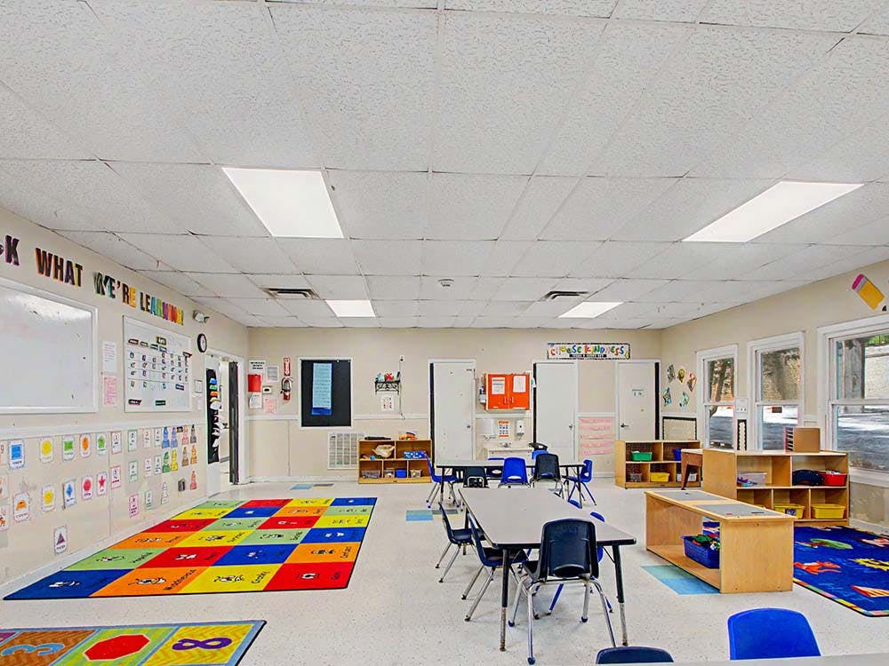 Empty classroom with colorful rugs and small tables with chairs