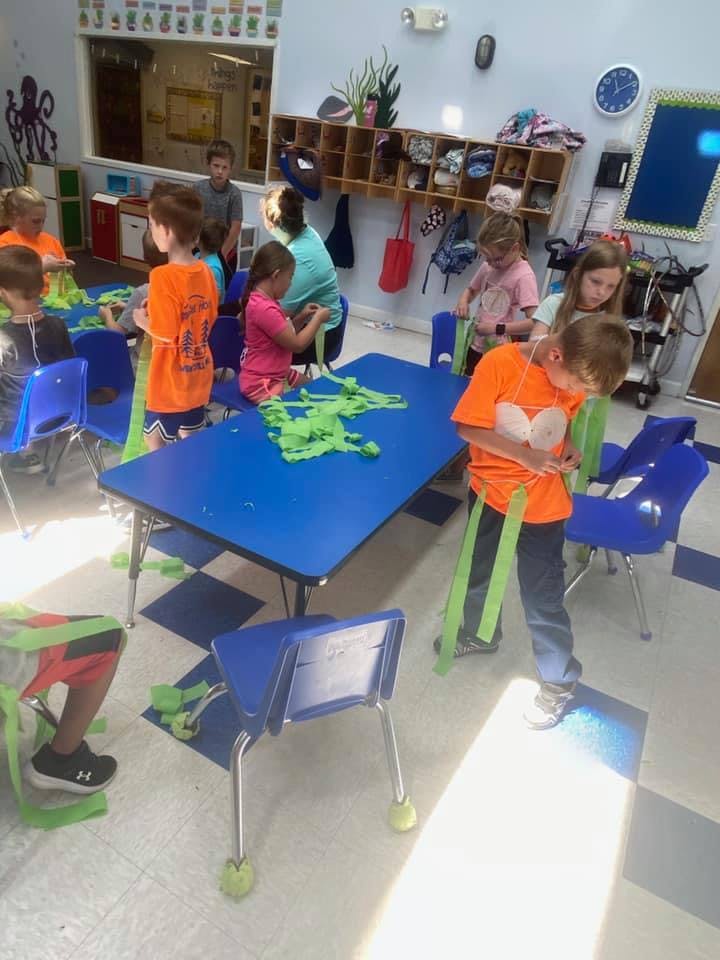 Children and adults in a classroom working with green craft materials