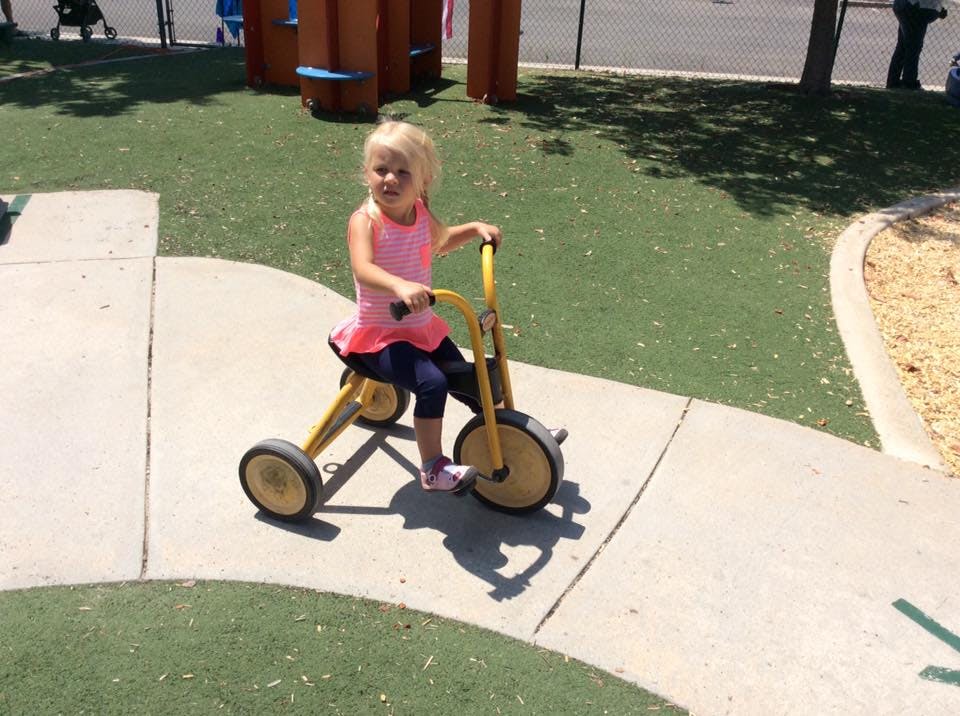 Child on a tricycle on a paved path
