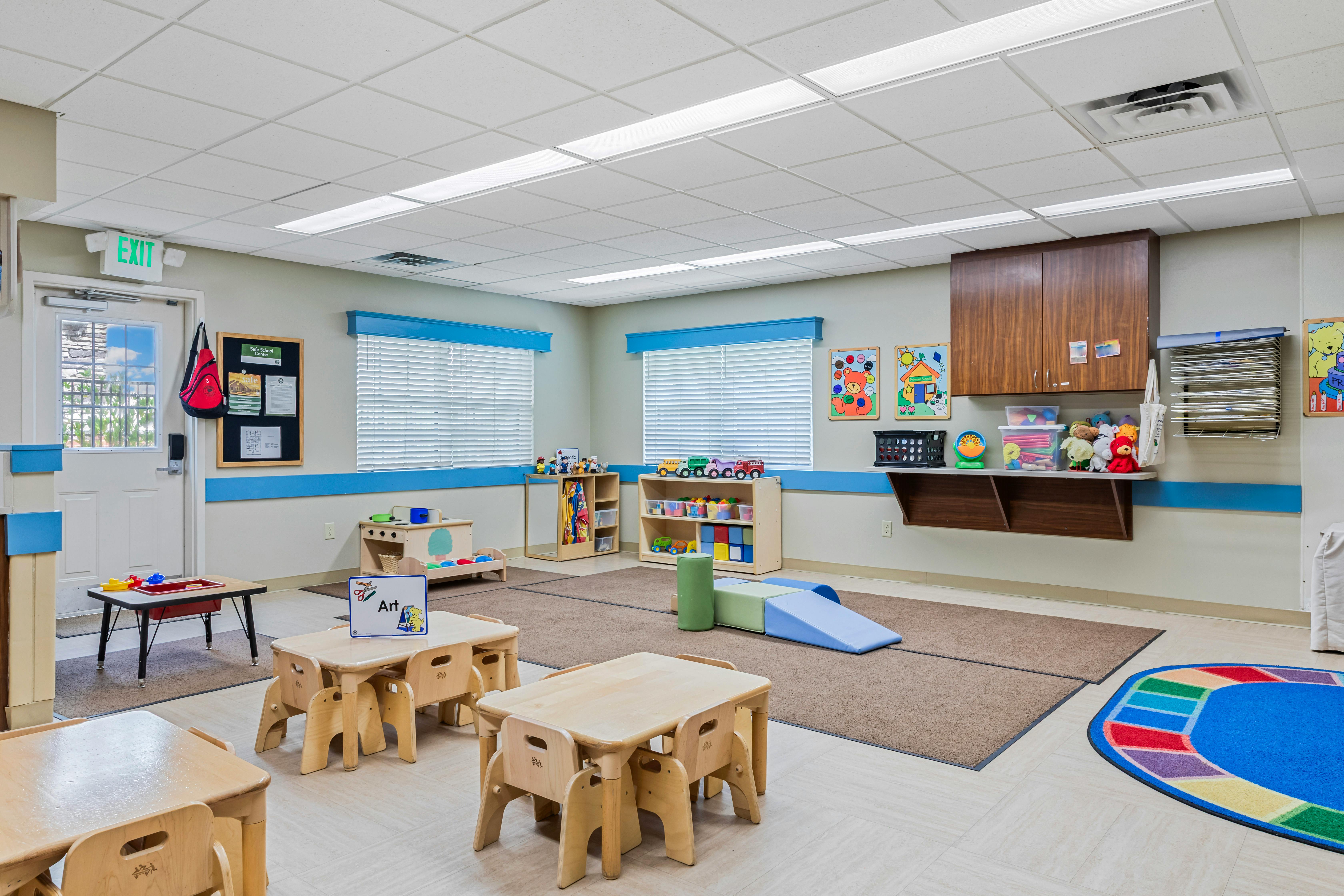 Classroom with small tables, chairs, and shelves filled with toys and activities