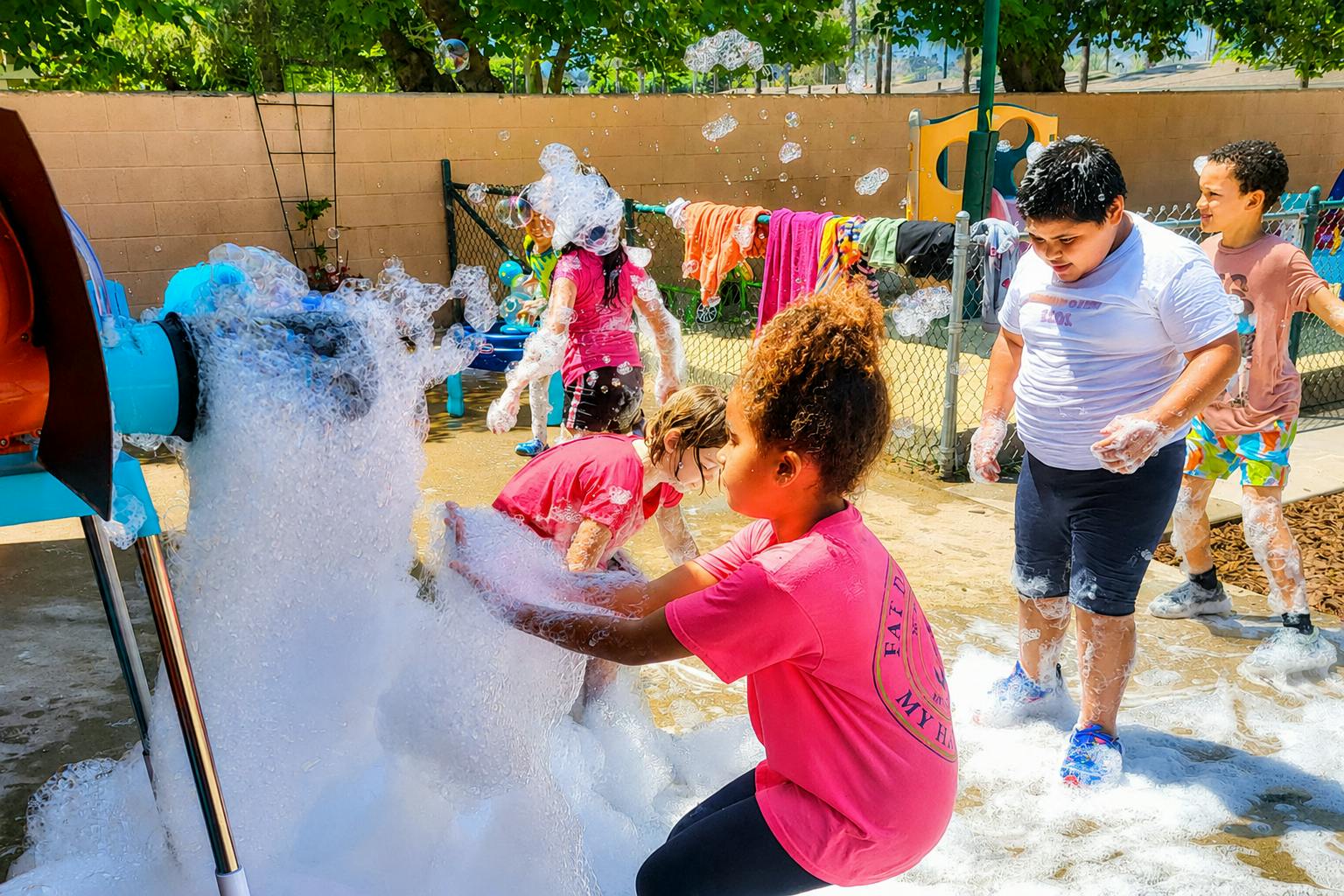 Children playing with foam from a bubble machine outdoors