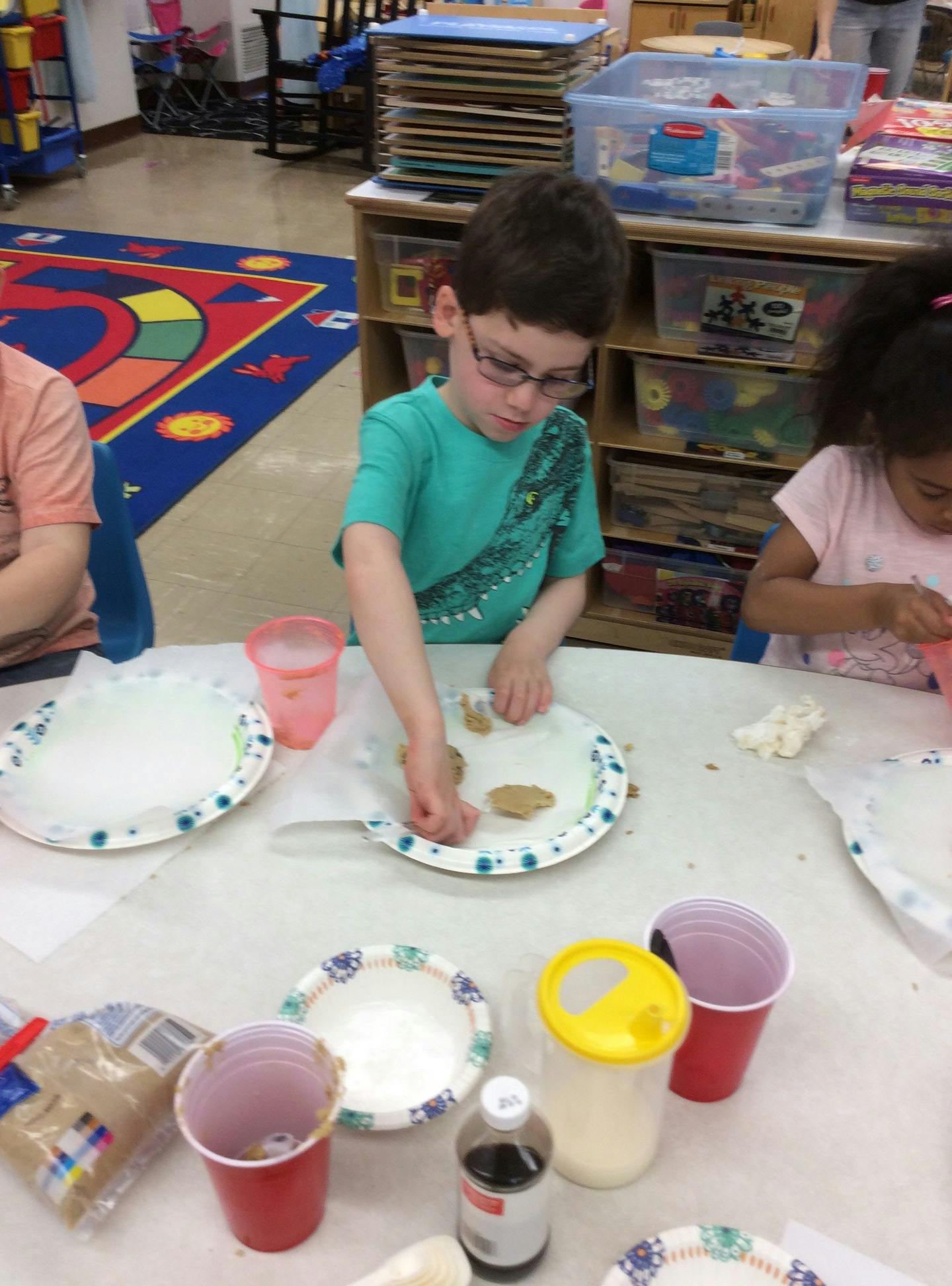 Child in glasses decorating cookies at a table