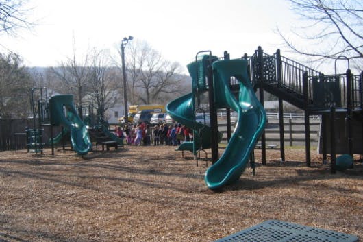 Playground with green slides and a group of people in the background