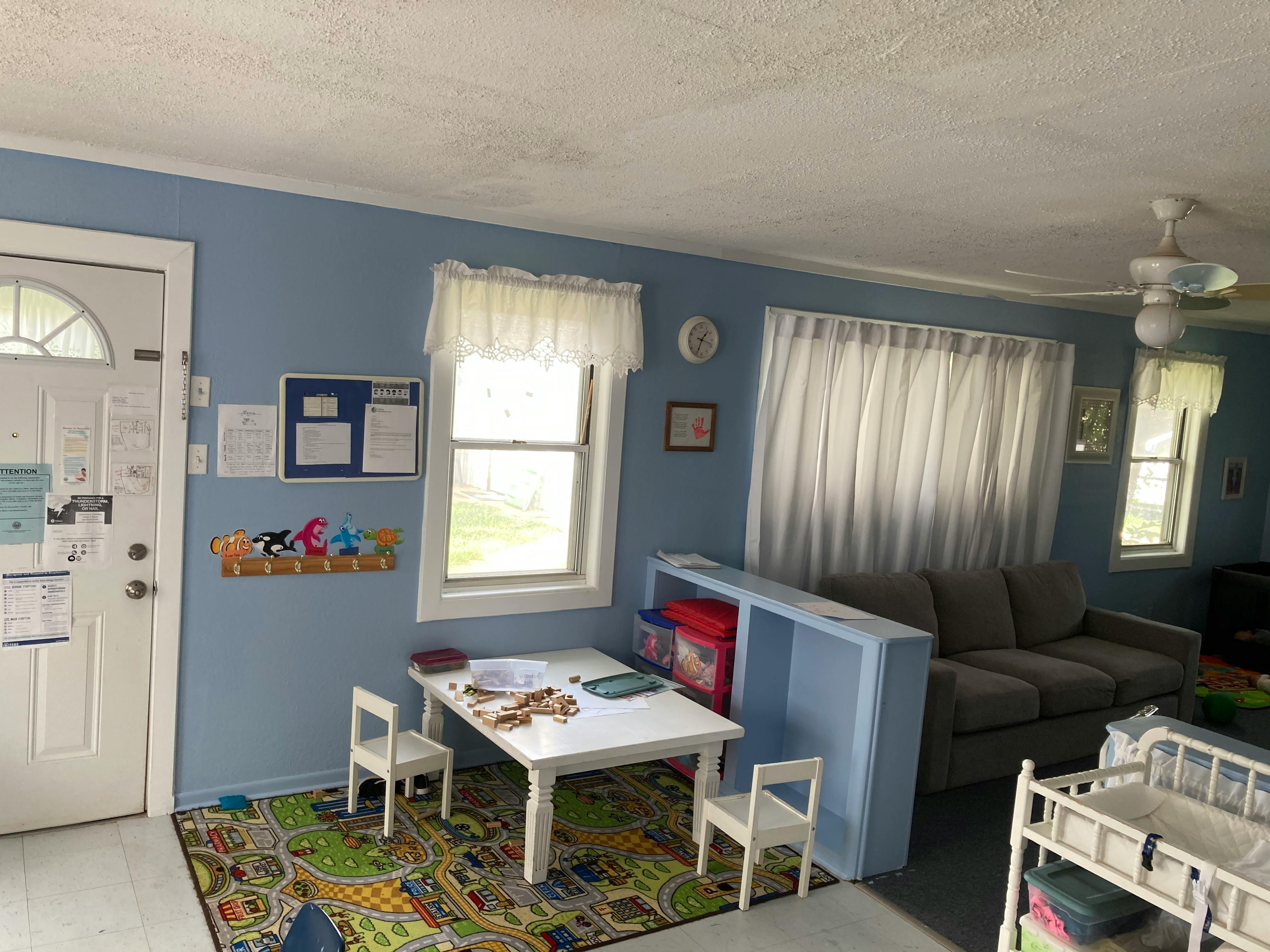 Playroom with small table and chairs, sofa, and crib