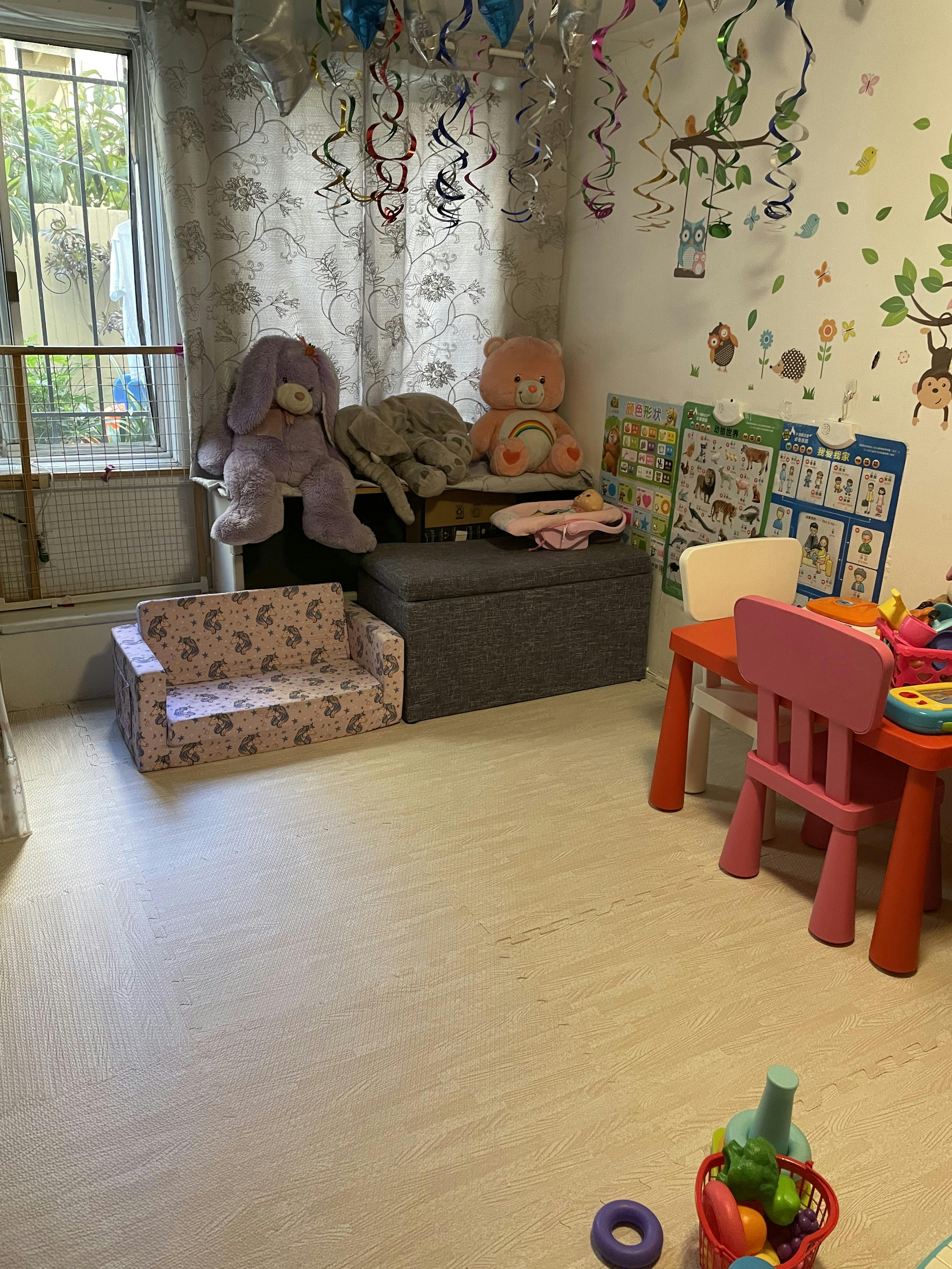 Children's playroom with stuffed animals, a small couch, and a table with chairs