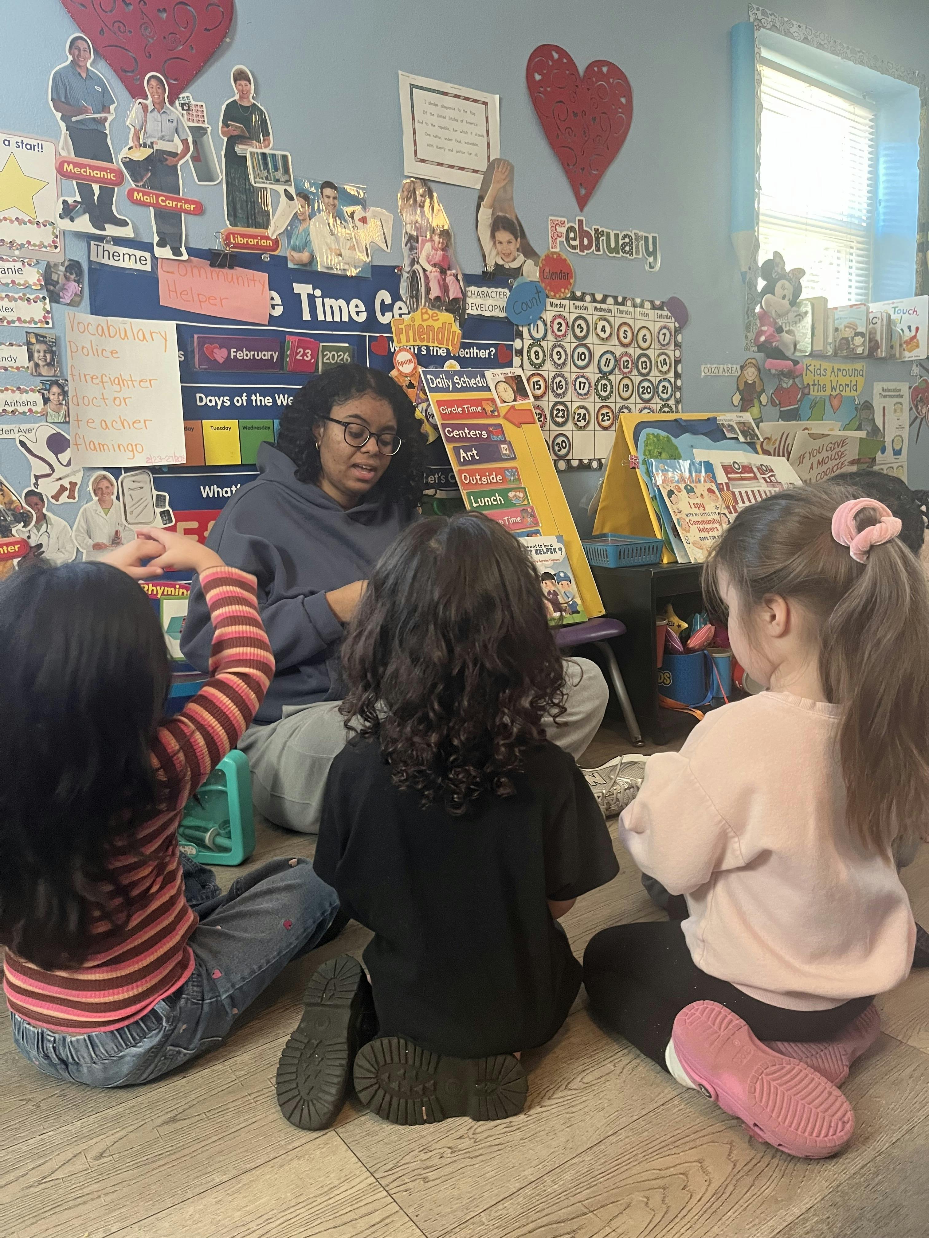 Teacher and three children sitting on the floor in a classroom