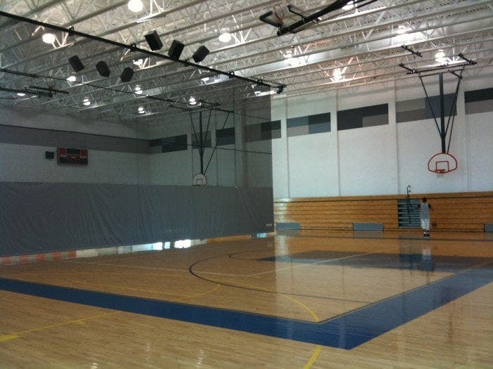 Empty basketball court with a person standing near a hoop