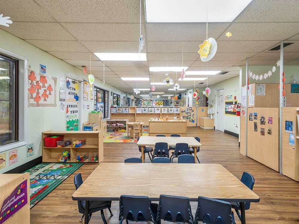 Empty colorful preschool classroom with small tables and chairs