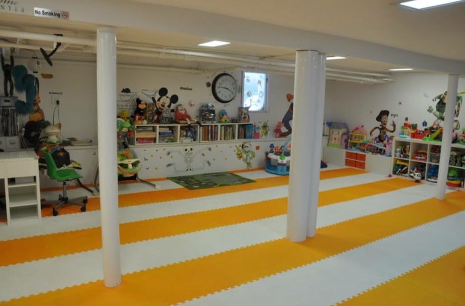 Playroom with orange and white striped floor, shelves of toys, and wall decorations