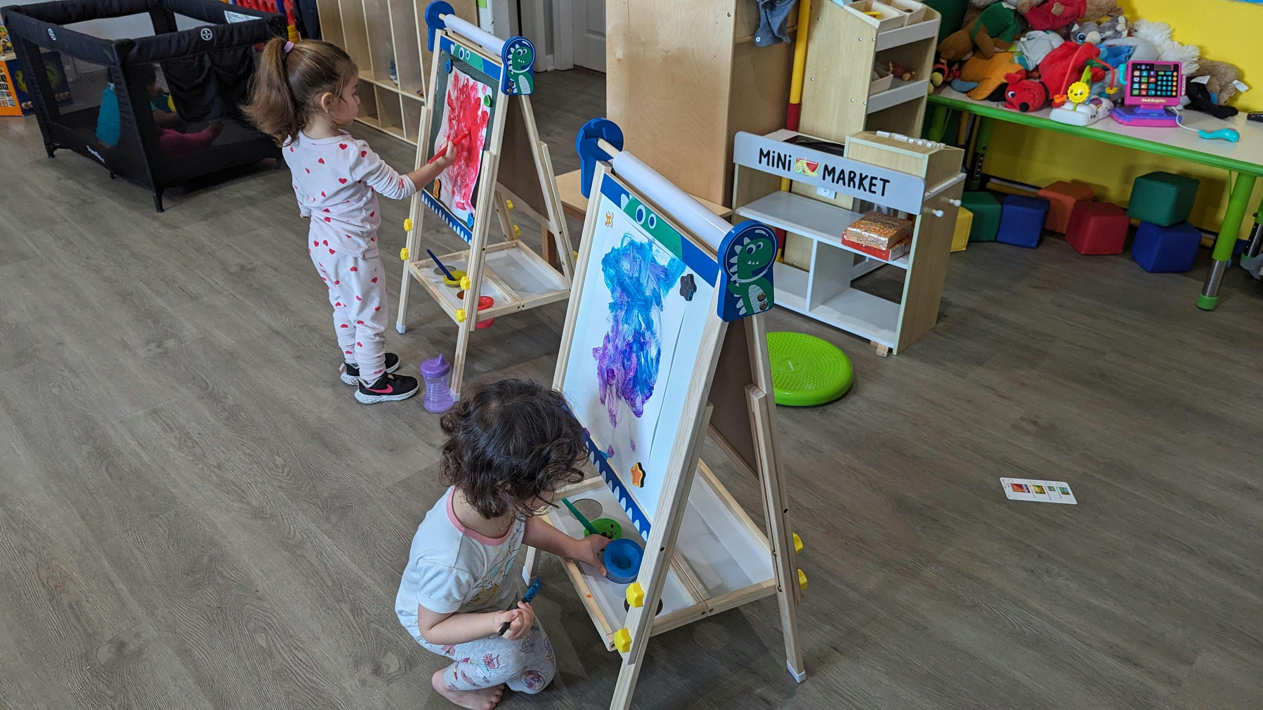 Two children painting at easels in a classroom