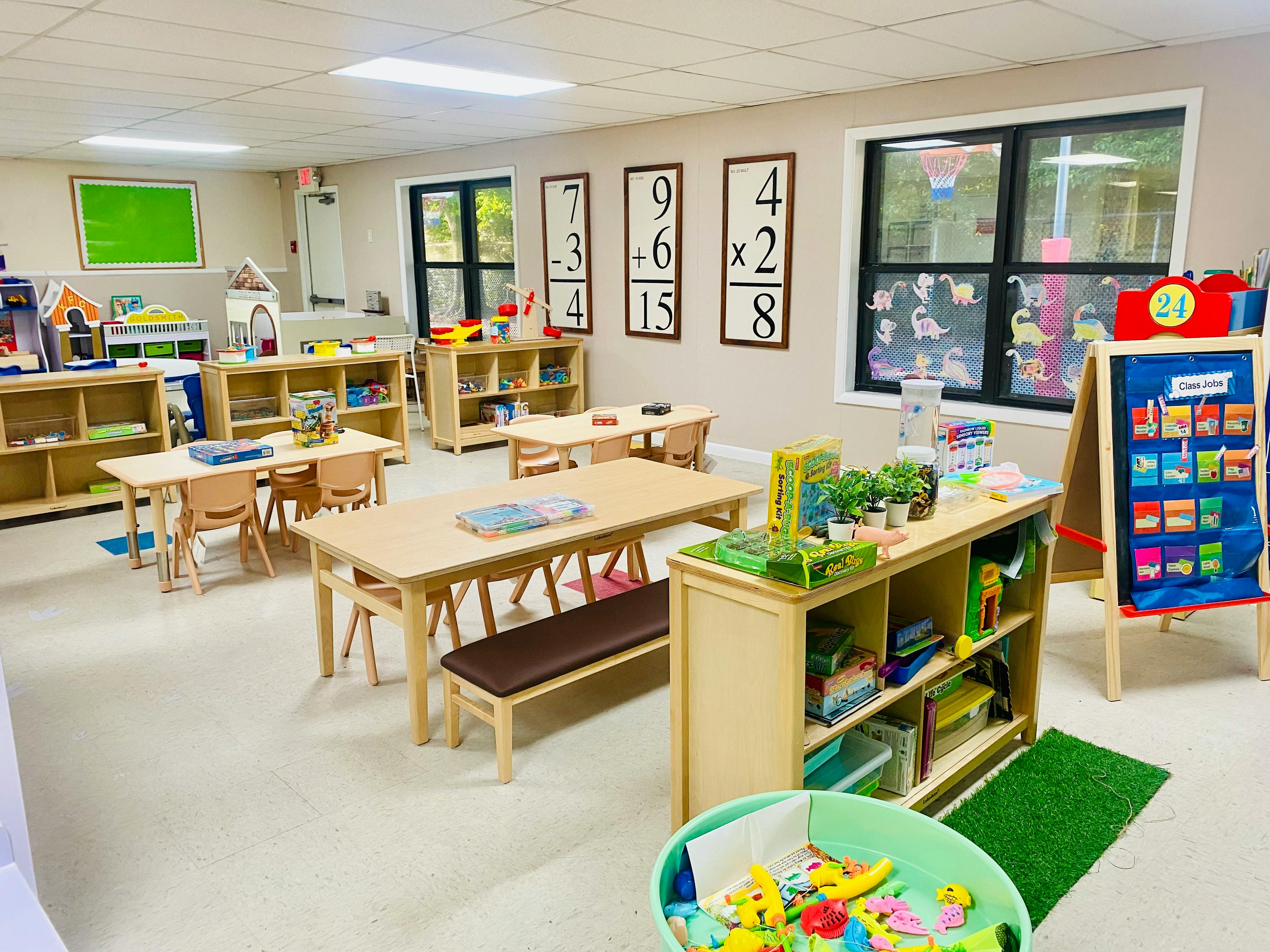 Classroom with small wooden tables, chairs, and shelves