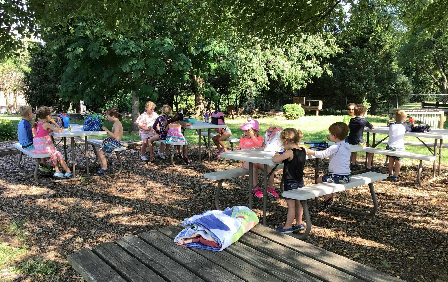 Children sitting at picnic tables outdoors