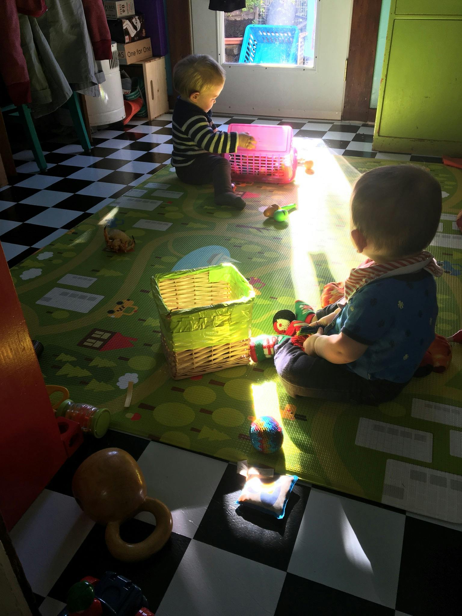 Two children playing with toys on a mat