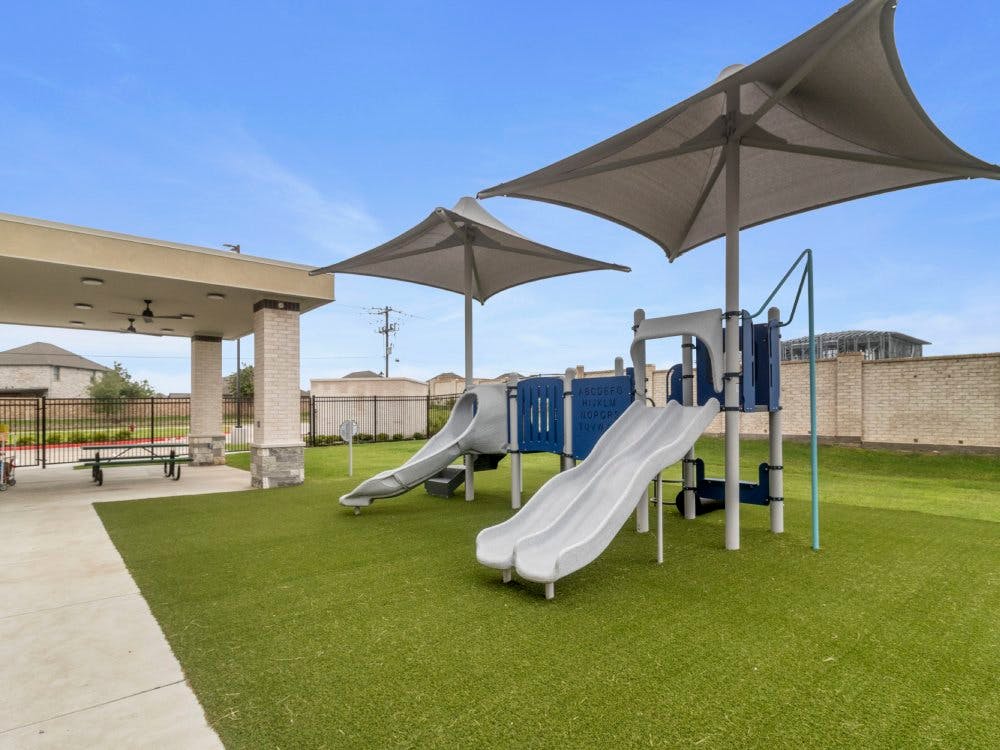 Playground with slides, shade structures, and an adjacent covered patio area