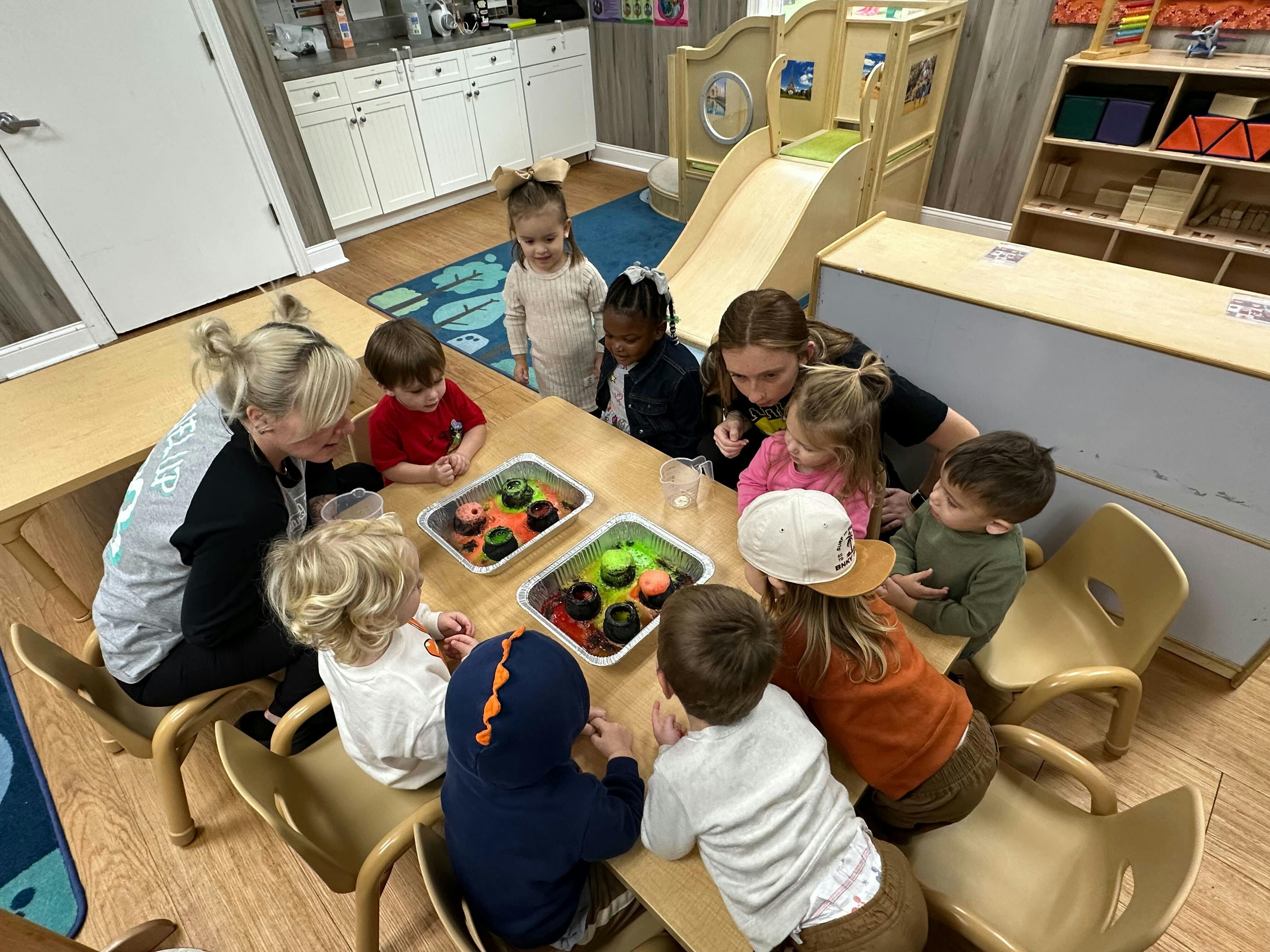 Adults and children gathered around a table with sensory bins