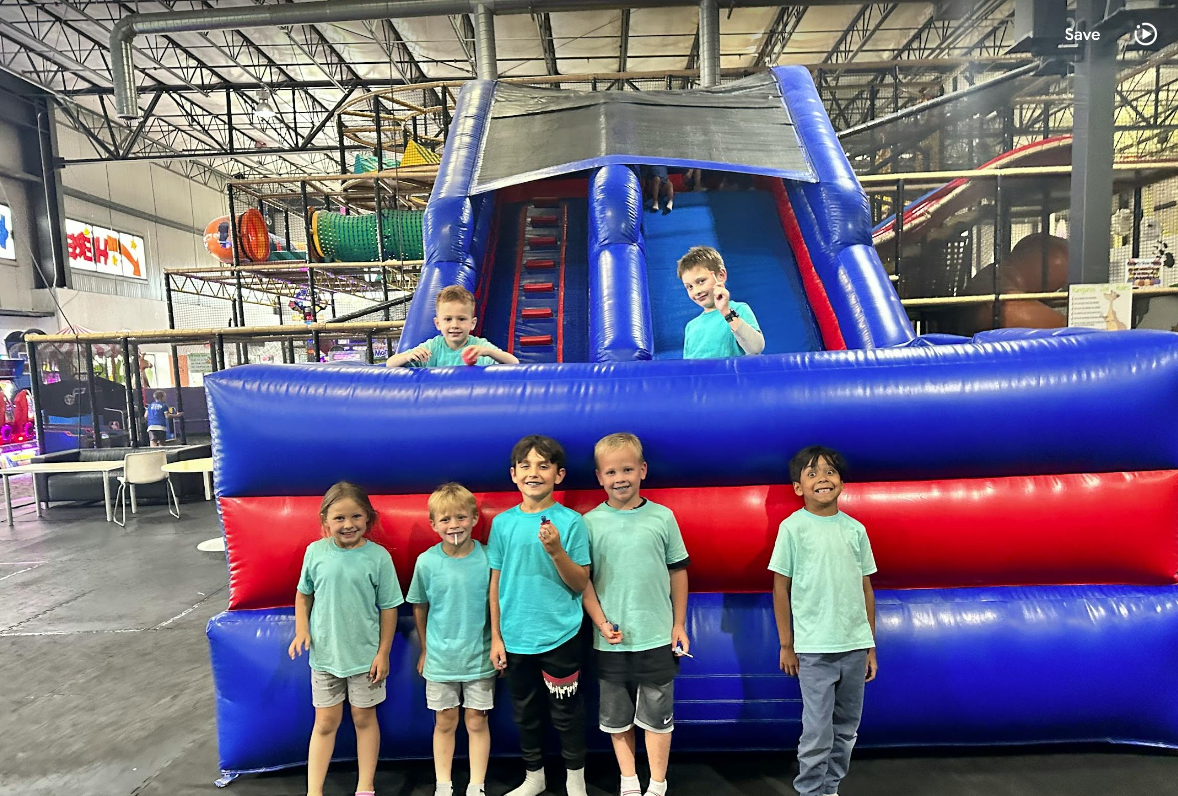 Children standing on and in a large blue and red inflatable play structure