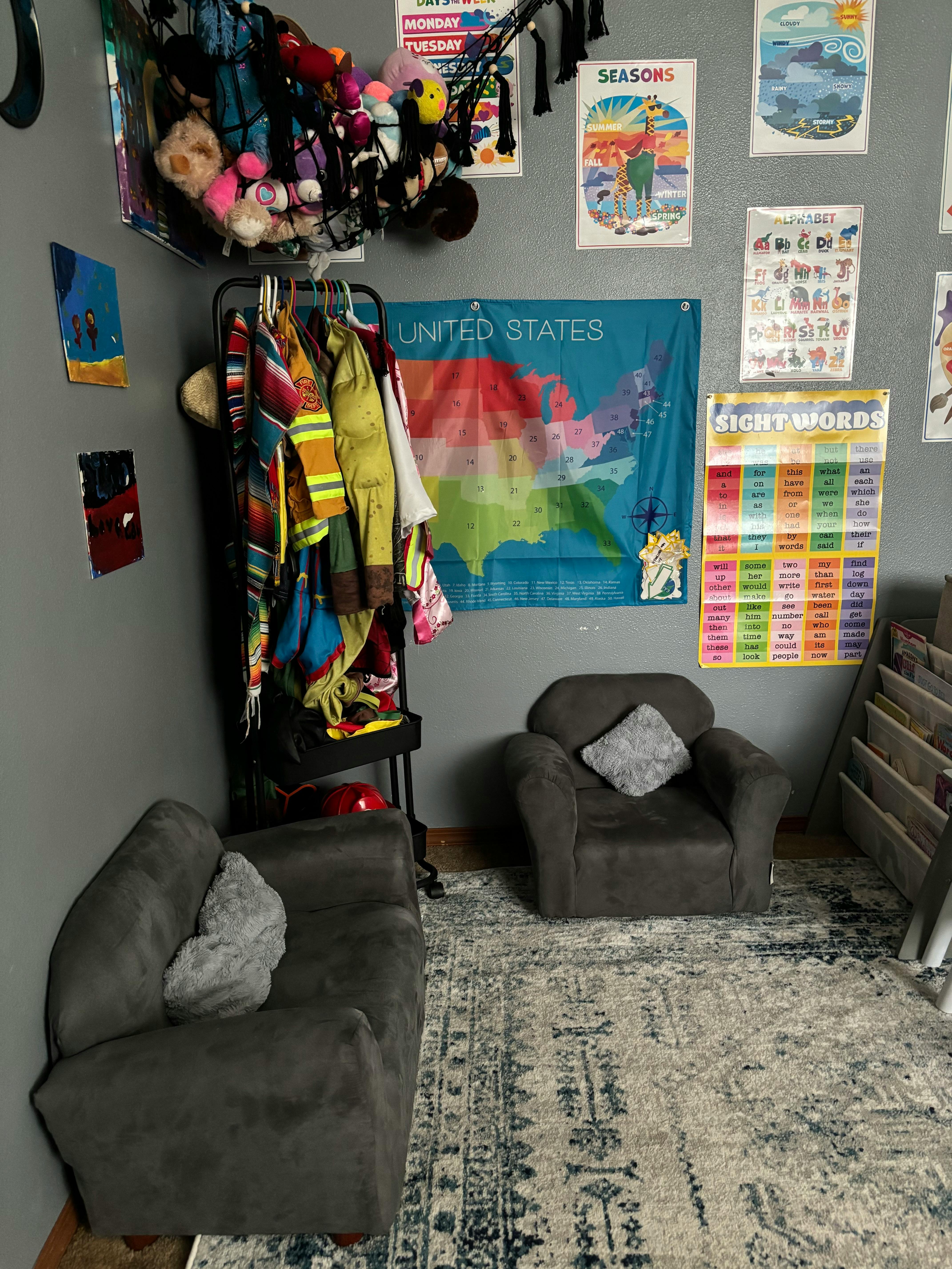 Children's play area with small chairs, clothes rack, and educational posters