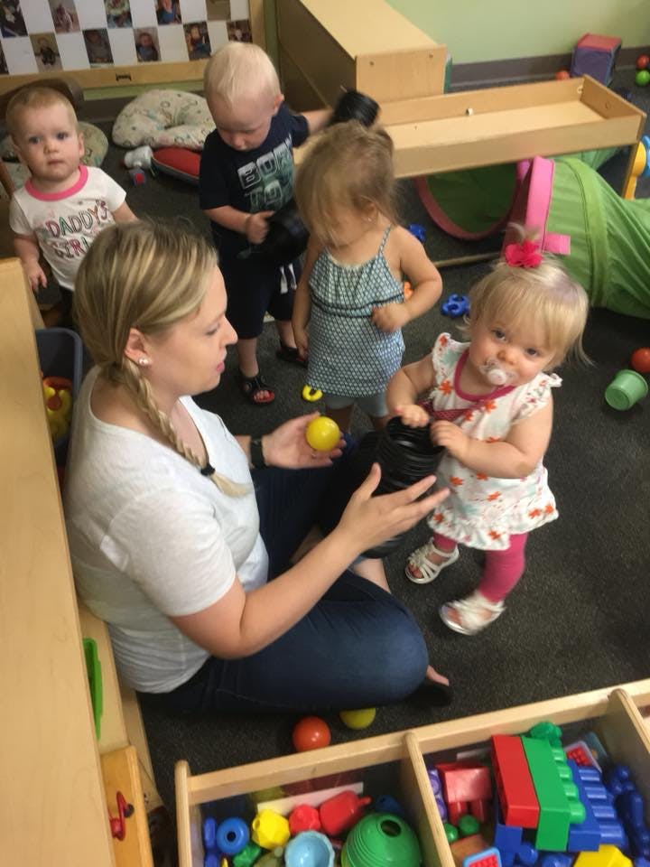 Adult and multiple children playing with toys in a room