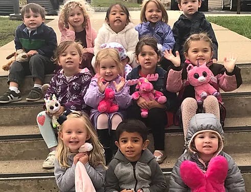 Group of children sitting on steps with stuffed animals
