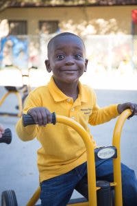 Child in yellow shirt riding a tricycle