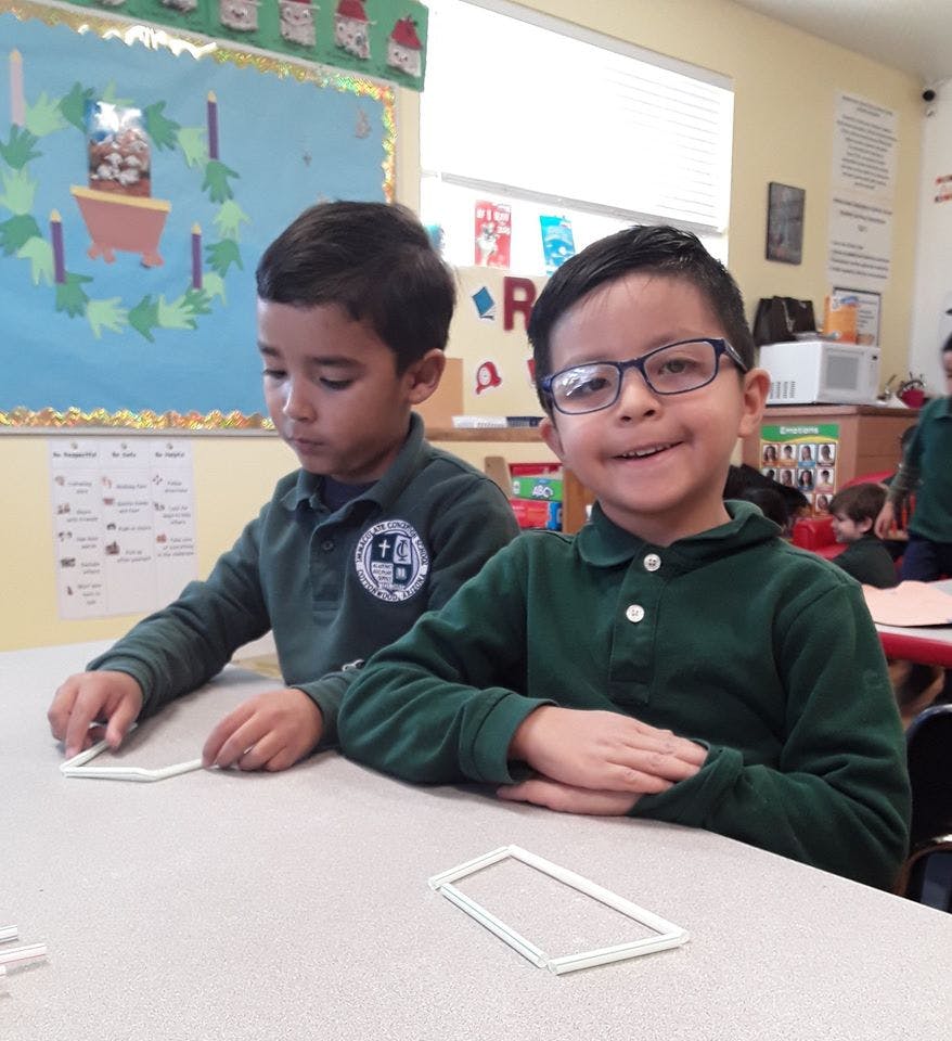 Two children at a table, one looking at the camera and one looking down