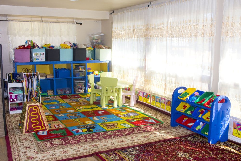 Playroom with colorful rug, small table and chairs, and toy shelves