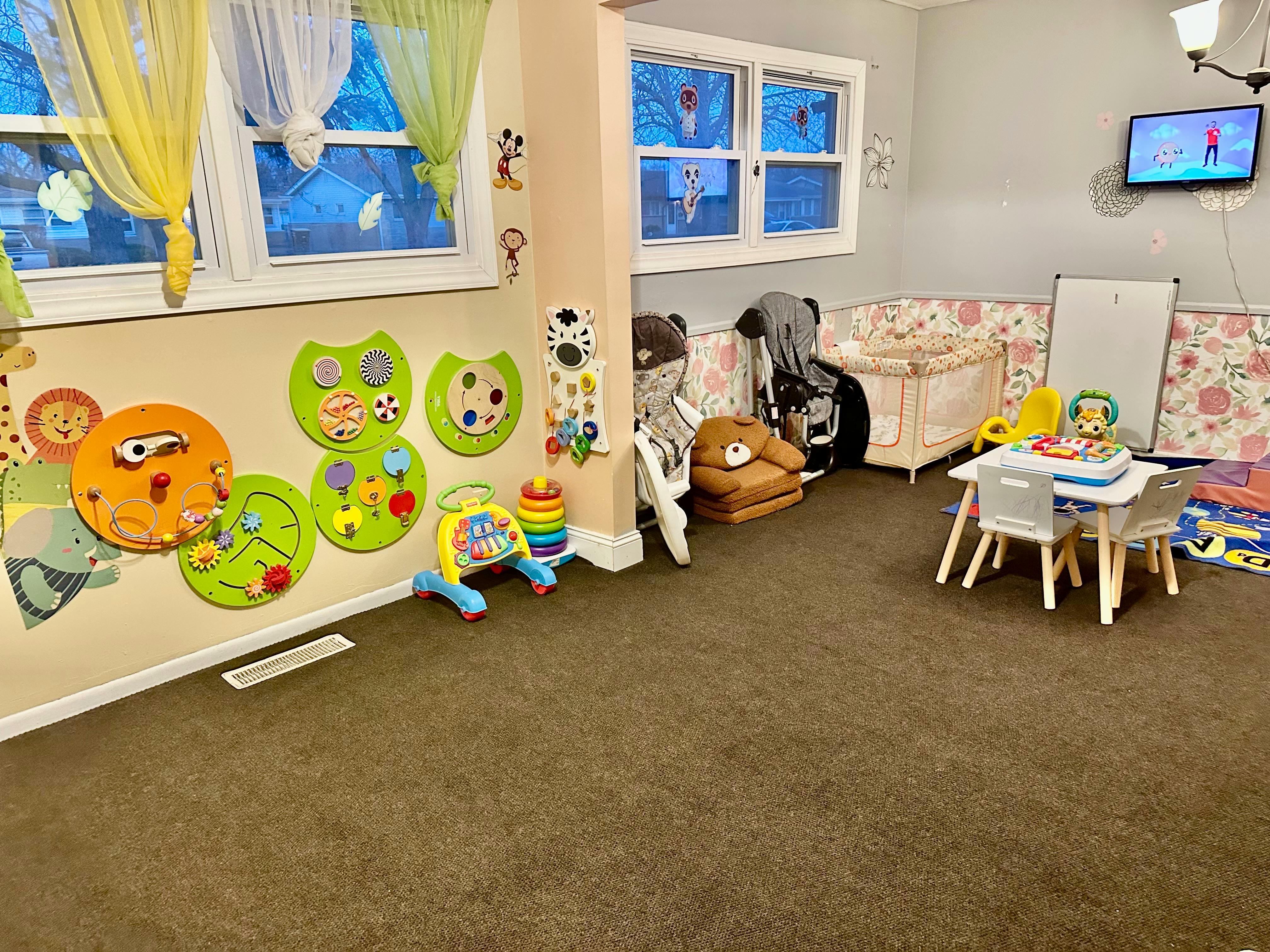 Playroom with wall decorations, small table and chairs, and crib