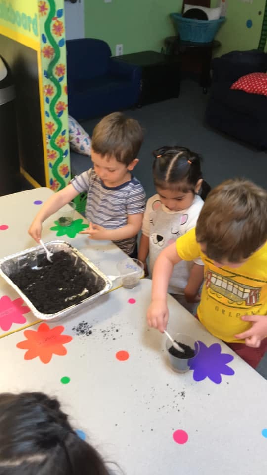Three children playing with dirt on a table