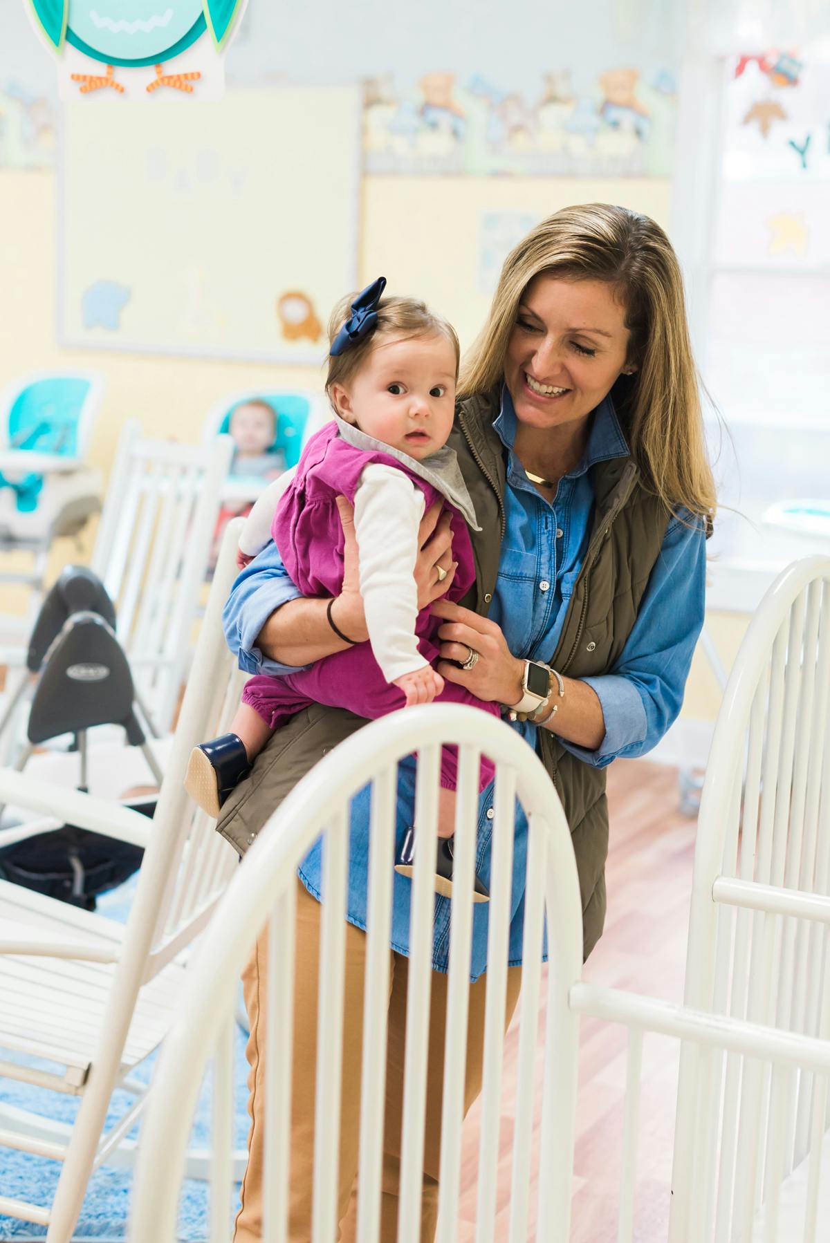 Person holding a child in a room with cribs
