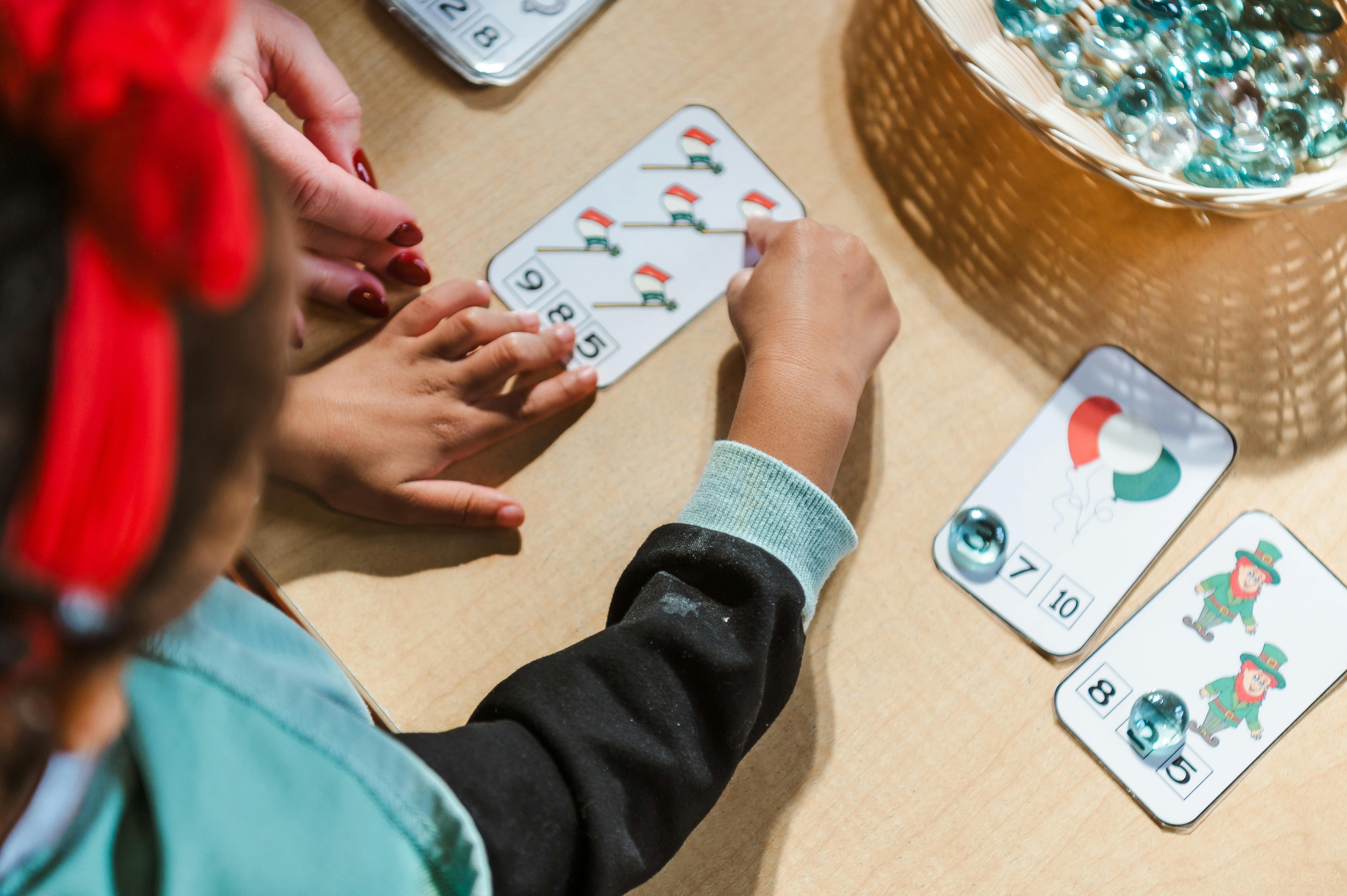 Two people playing a card game with marbles