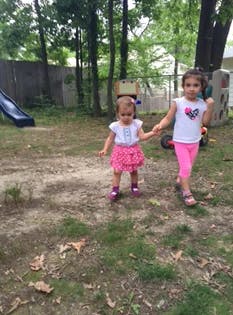 Two children holding hands and walking outdoors
