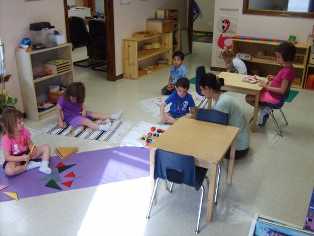 Children and an adult playing with toys in a classroom
