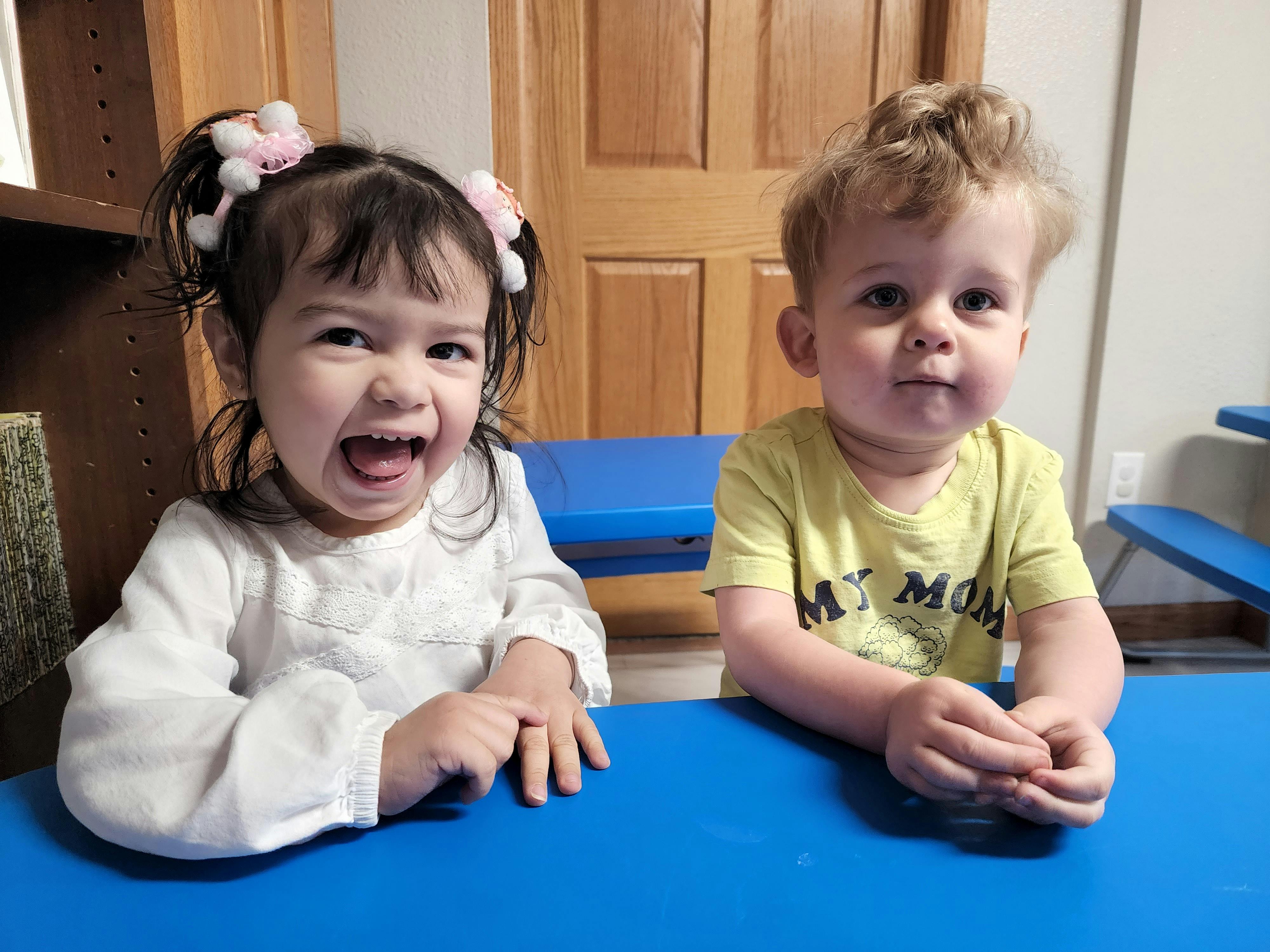 Two children sitting at a blue table