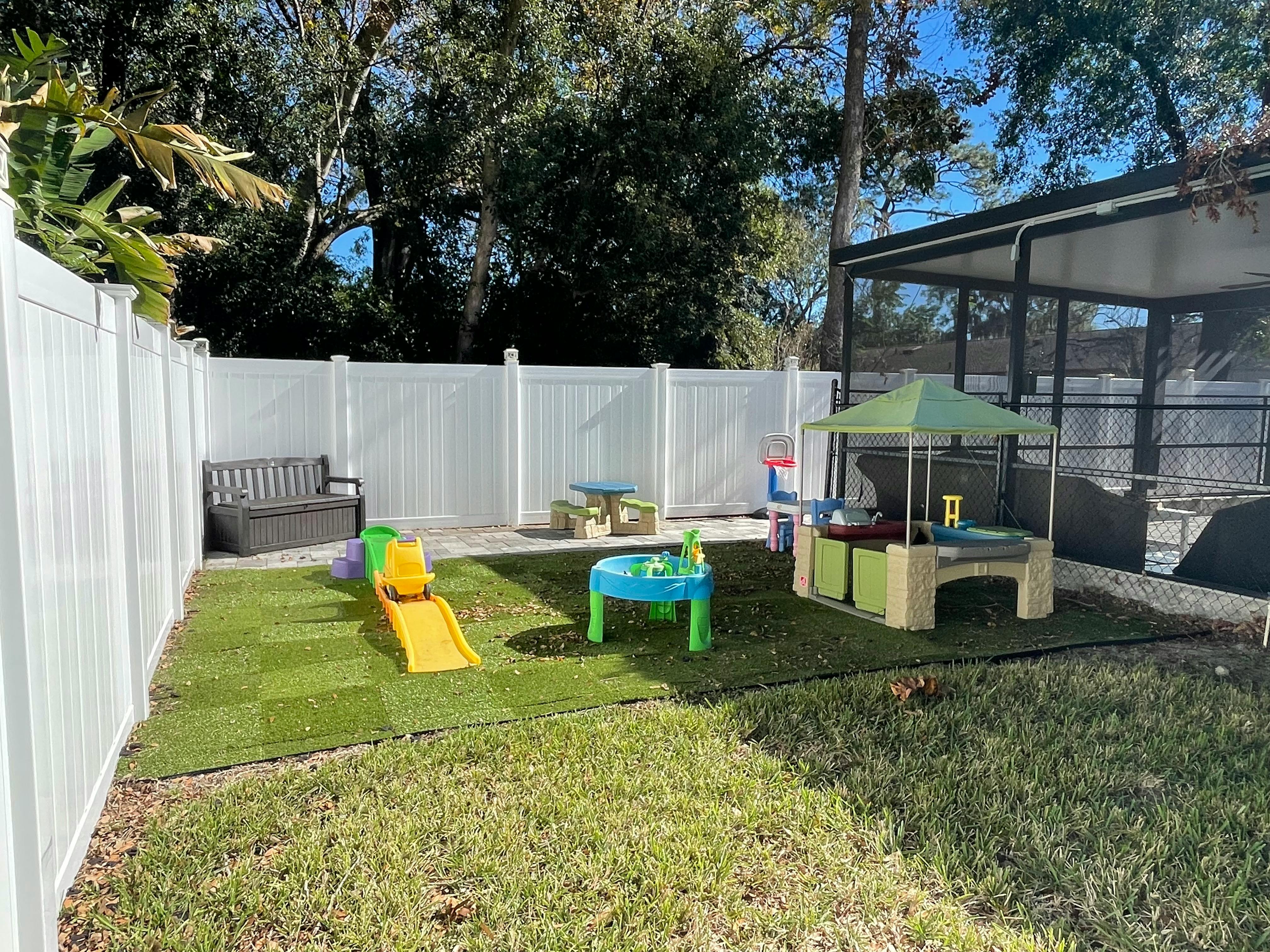 Backyard with artificial turf, white fence, and children's play equipment