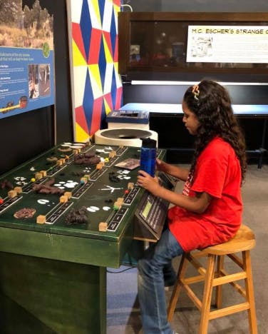 Child sitting at a green interactive display table