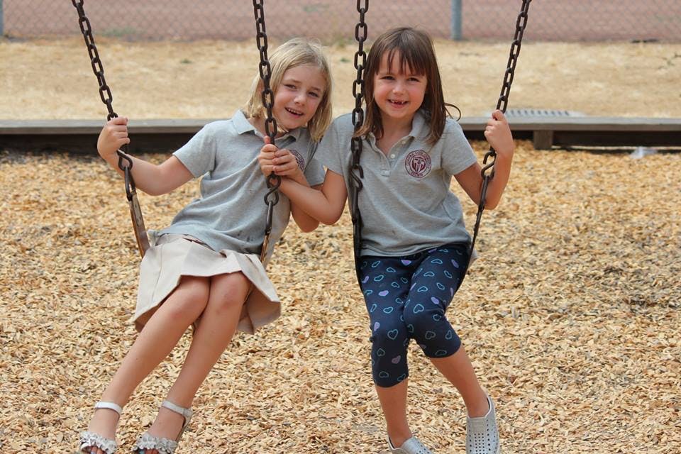 Two children sitting on swings on a playground