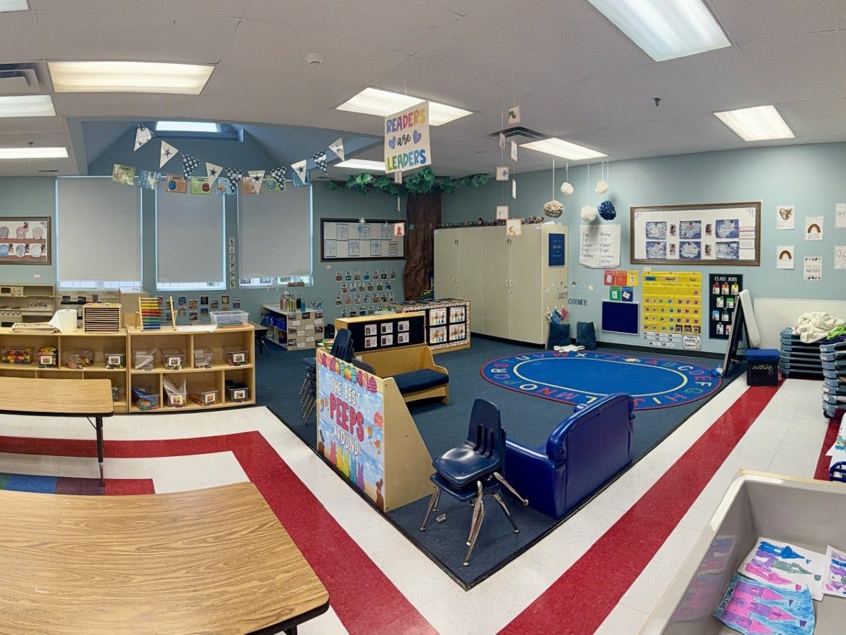 Colorful classroom with a reading corner, tables, and learning materials