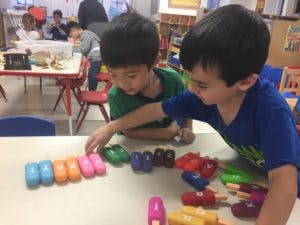 Two children playing with colorful toys at a table