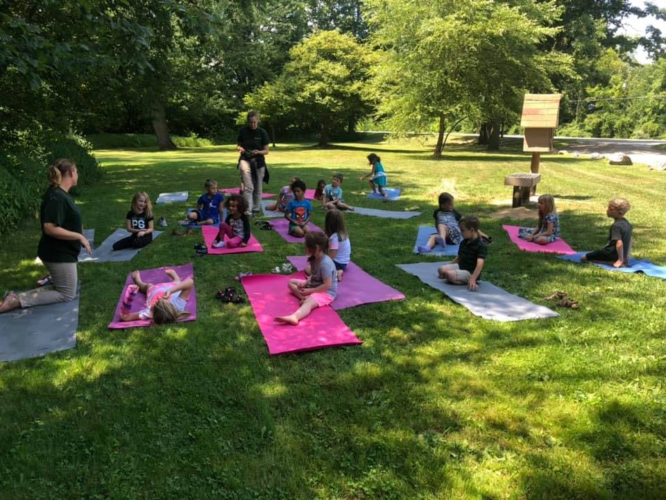 Adults and children on yoga mats outdoors