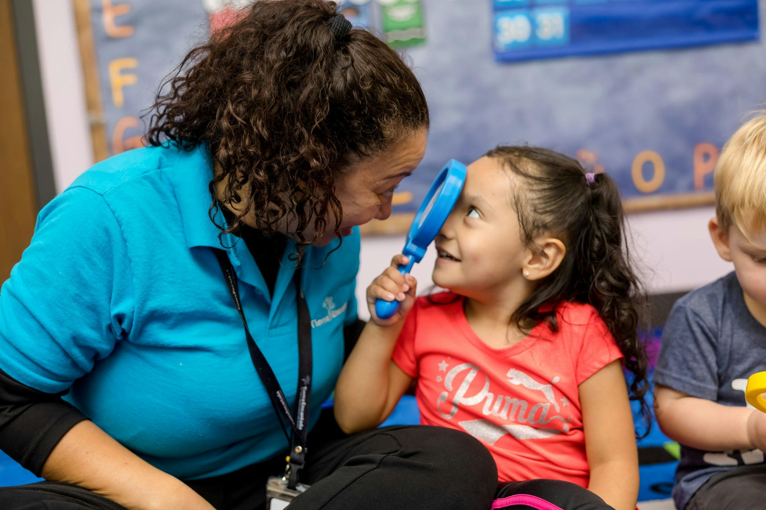 Person and child looking at each other, child holding a magnifying glass