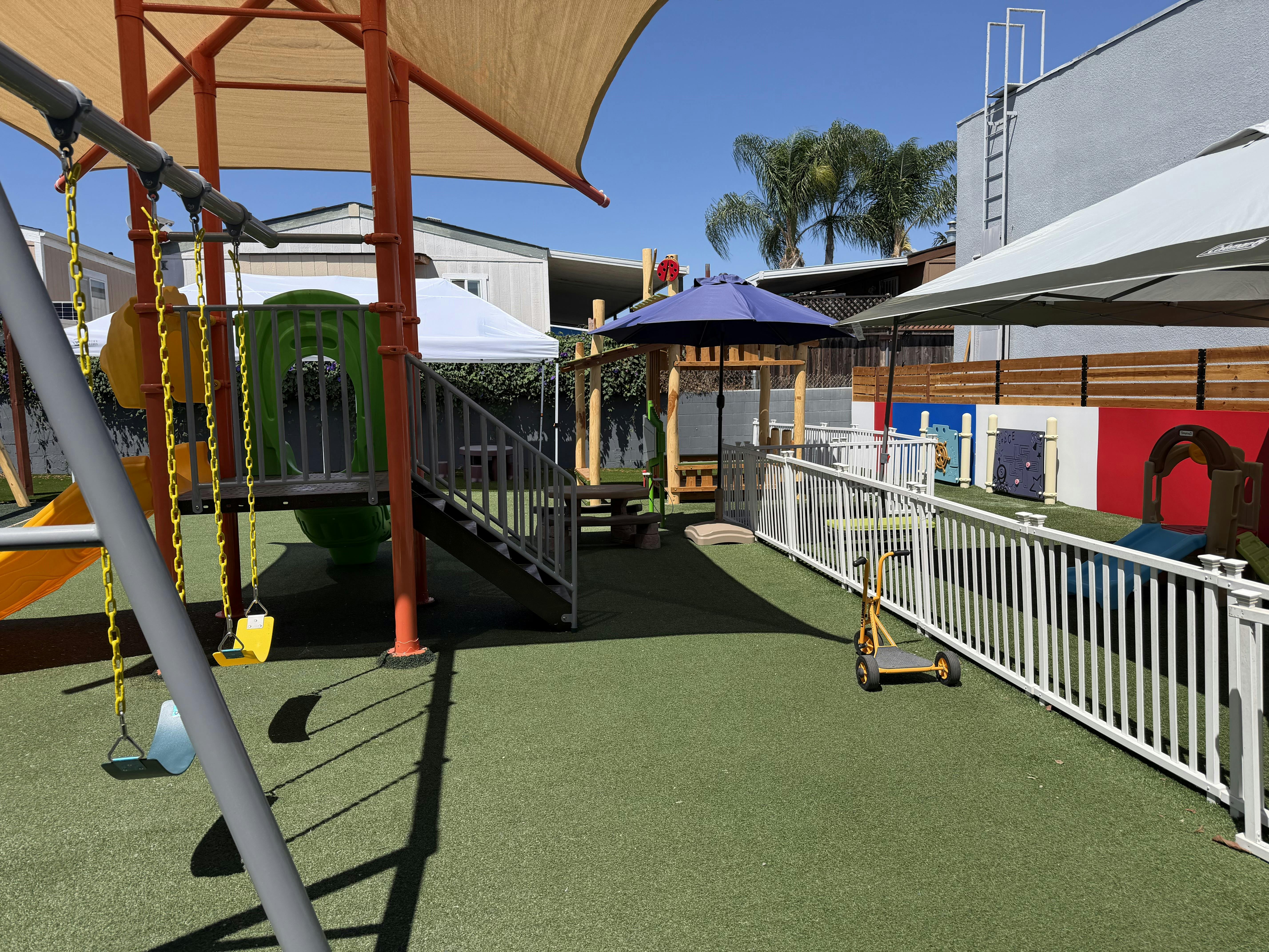 Playground with swings and a slide under a canopy