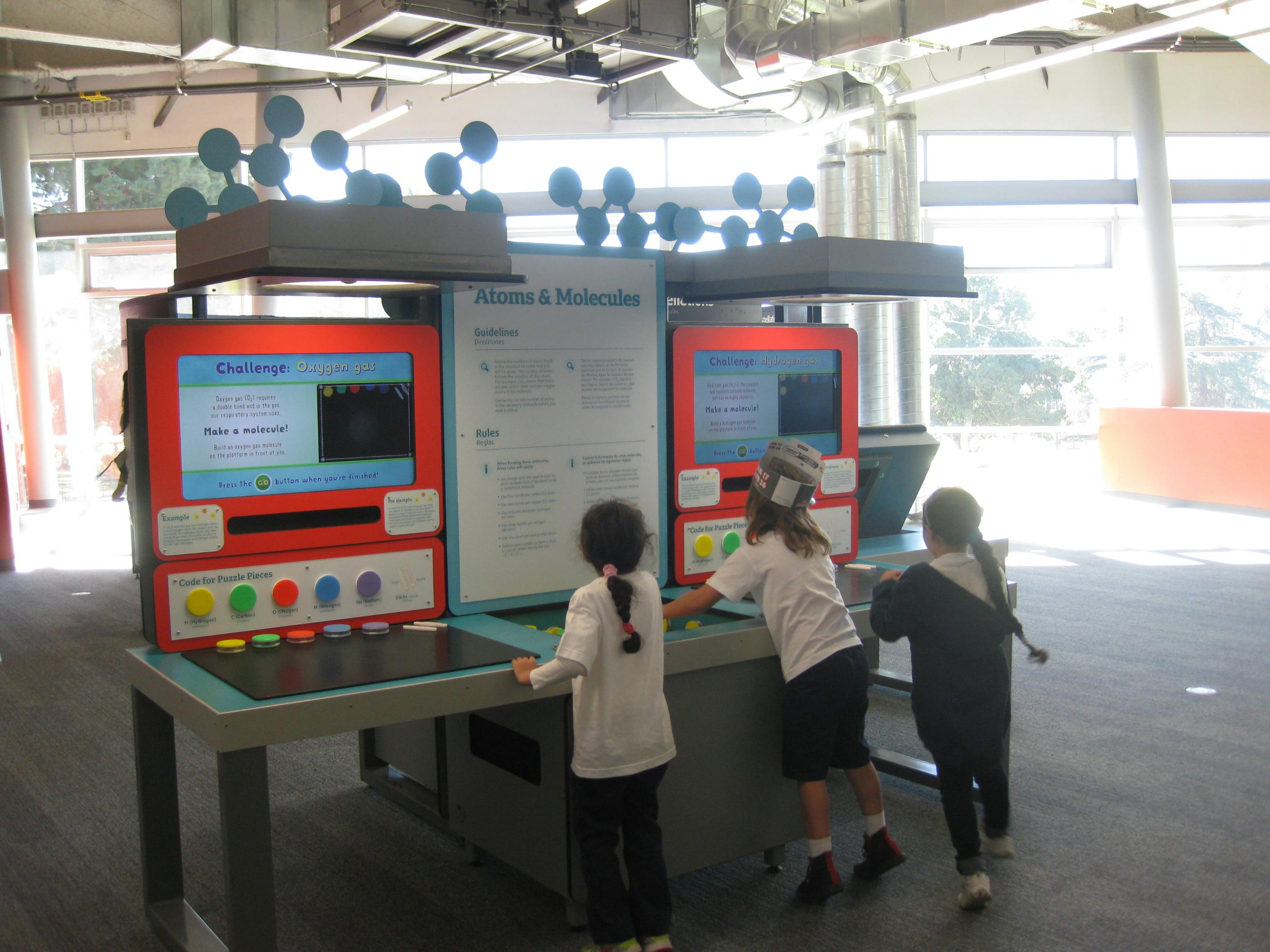 Three children interacting with an educational exhibit
