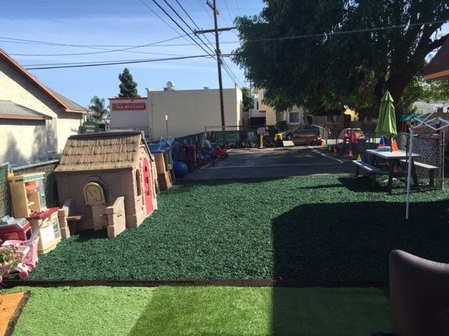Backyard with artificial turf, playhouse, and picnic table