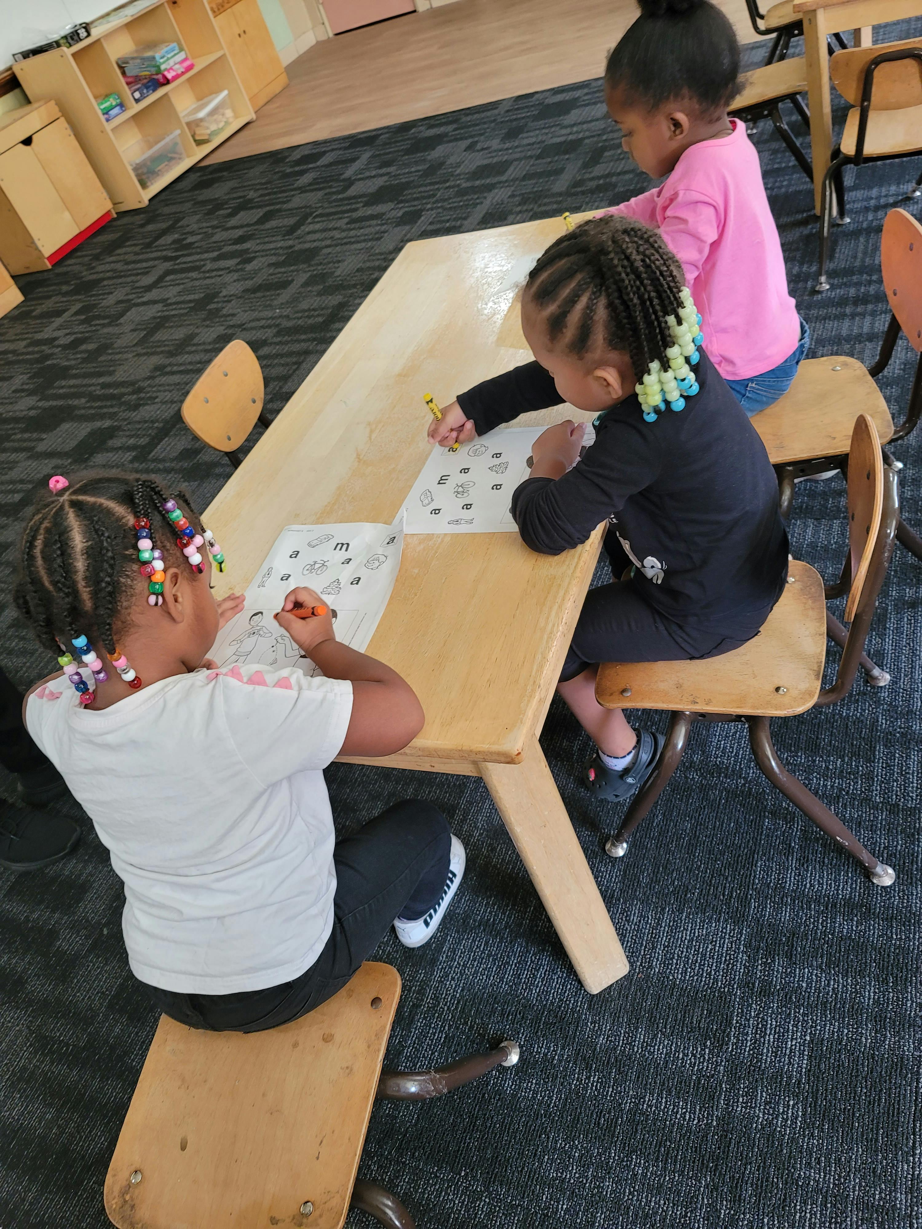 Three children sitting at a table drawing