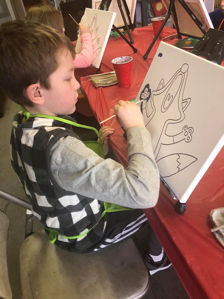 Child painting a fox outline on a canvas
